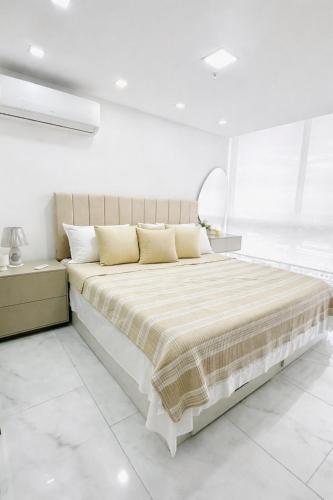 a white bedroom with a large bed with yellow pillows at Zen Living Sky Suite in SamborondÃ³n