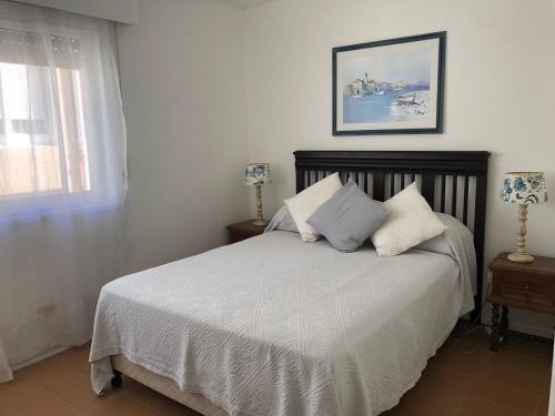 a bedroom with a bed with white sheets and a window at Celestia in Punta del Este