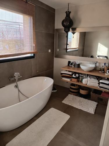 a bathroom with a large white tub and a sink at Chambre d'hôtes chez l' habitant Villa Bianca in Peaugres