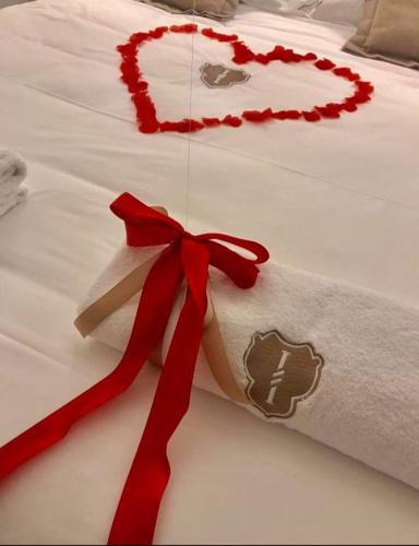 a white bed with a red ribbon on it at RODRIGUEZ Luxury Suite in Ostuni