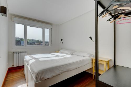 a white bedroom with a bed and a window at Orio Playa in Orio