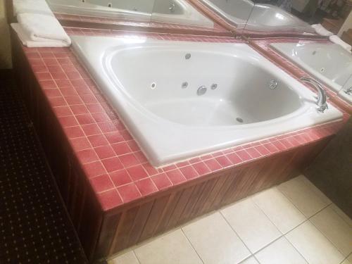 eine Badewanne im Bad mit roten Fliesen in der Unterkunft Travelers Lodge in Atco
