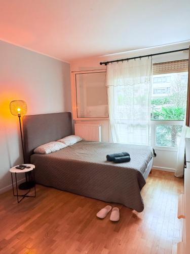 a bedroom with a bed and a window with slippers at Apparemment agréable in Levallois-Perret