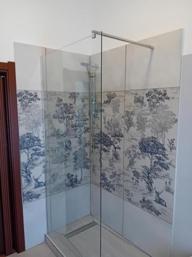 a glass shower stall with a blue and white wallpaper at Ca' melindetta in Recetto