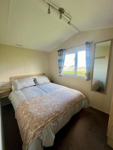 a bedroom with a large bed and a window at Seaside Caravan in a Leisure Park with WiFi & Parking - 3 bedrooms in Meliden