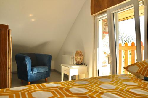 a bedroom with a bed and a chair and a window at La Giraudière avec climatiseur 2 à 4 personnes in Soulgé-sur-ouette