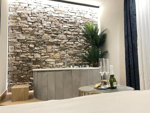 a room with a stone wall and a table with wine glasses at Mape Loft Rural ALJIBE in Algar