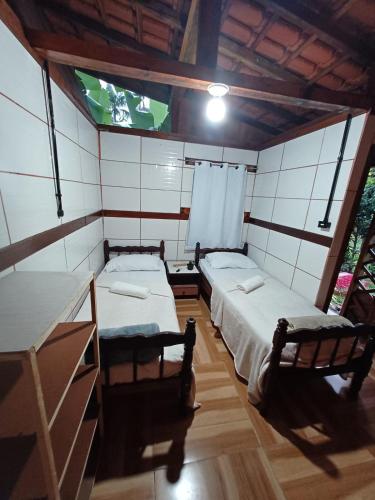 a room with two beds and a tv in it at Pousada Oliveira Ramos in Lumiar