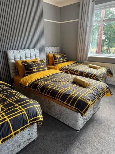 two beds in a room with yellow and black blankets at Spacious 3BR Flat near Newcastle Centre in Saint Peters