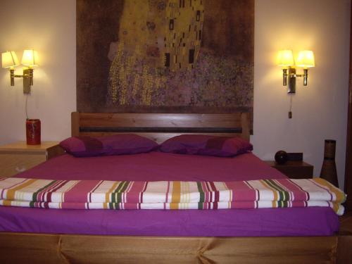 a bedroom with a purple bed with a painting on the wall at Evelin Apartment in Portaria