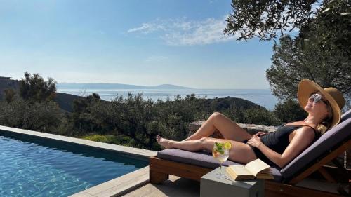 a woman sitting in a chair next to a swimming pool at Petres Luxury Villas with heated private pool in Agia Galini
