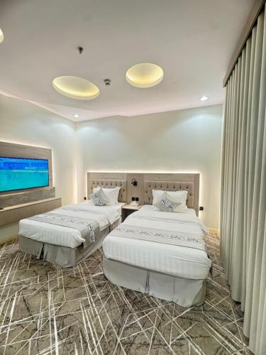 two beds in a room with a flat screen tv at عز الاصالة للشقق المخدومة تصنيف اقتصادي in Taif