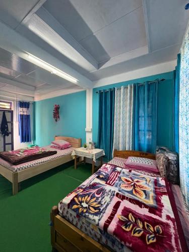 two beds in a room with blue walls at SOUPRIYA Impression Homestay in Pedong