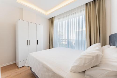 a bedroom with a white bed and a large window at VISTA SERENA Ermenek in Altınkum