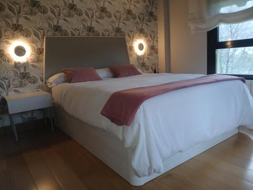a bedroom with a large white bed with red pillows at Leku eder in Areatza