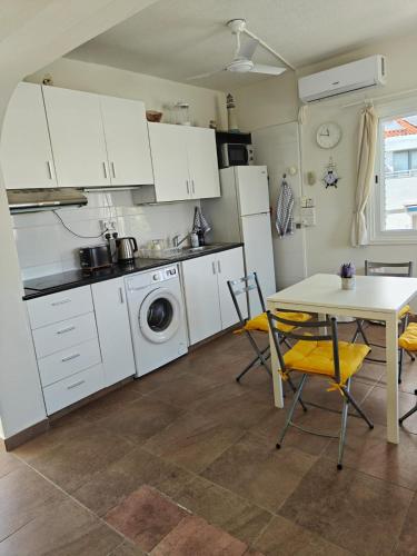 a kitchen with white cabinets and a table with chairs at Green Bay Beach Escape in Protaras