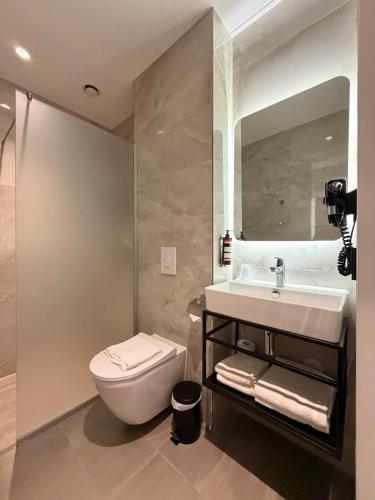 a bathroom with a sink and a toilet and a mirror at OZO Hotels Antares Amsterdam Schiphol Airport in Hoofddorp