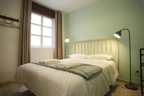 a bedroom with a bed with white sheets and a window at Casa do jato in Muros
