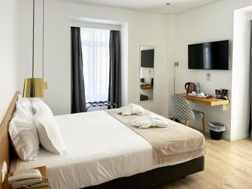 ein Schlafzimmer mit Bett, Schreibtisch und Fernseher in der Unterkunft Hotel Solaris in Setúbal