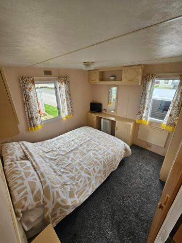 a small bedroom with a bed and two windows at Ingoldmells golden sands plot 152 in Ingoldmells