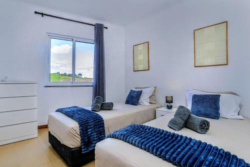 two beds in a room with a window at Azorina Lodge in Ponta Delgada