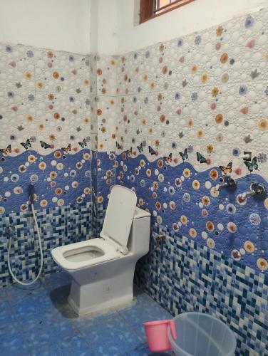 a bathroom with a toilet and a blue tiled wall at Balaji hotel in Badrinath