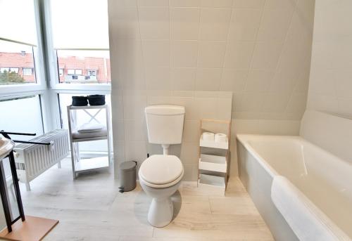 a white bathroom with a toilet and a bath tub at Sehr gemütlich und modern in Haldensleben