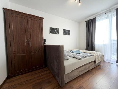 a bedroom with a bed and a wooden cabinet at Gustowny apartament in Inowrocław