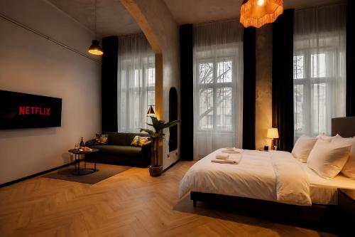 a bedroom with a bed and a couch and windows at Maroon & Moss Residence in Budapest