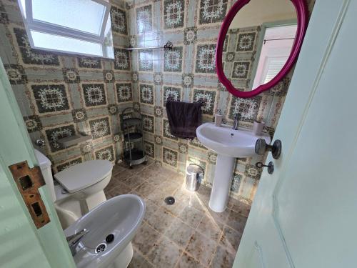 a bathroom with a sink and a toilet and a mirror at Casa Bonito in Vila Nova De Cacela