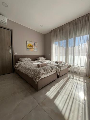 a bedroom with two beds and a large window at Κομψό studio με δωρεάν πάρκινγκ in Volos