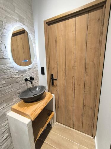 a bathroom with a sink and a wooden door at Escale à Clisson - Les jardins de Bali in Clisson