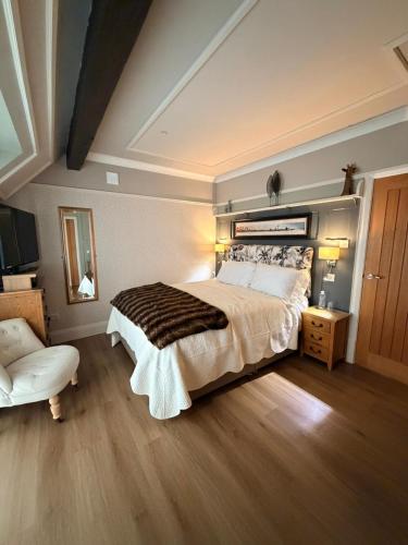 a bedroom with a large bed and a chair at Bryn Goleu Bed & Breakfast in Llandudno