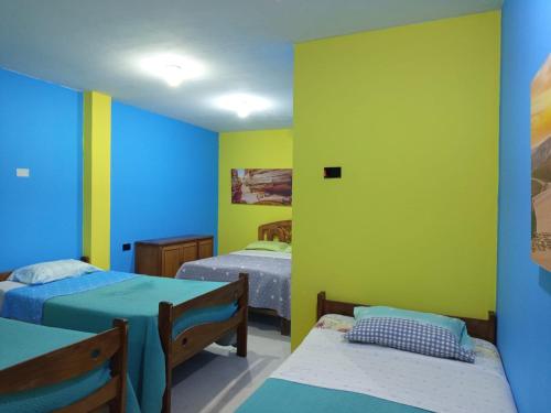 a room with two beds and yellow and blue walls at the silva house in Huacachina