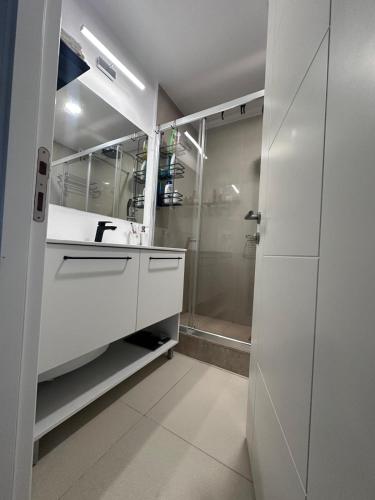 a white bathroom with a sink and a shower at Sunset Beach Studio by Blaxy Resort Olimp in Olimp
