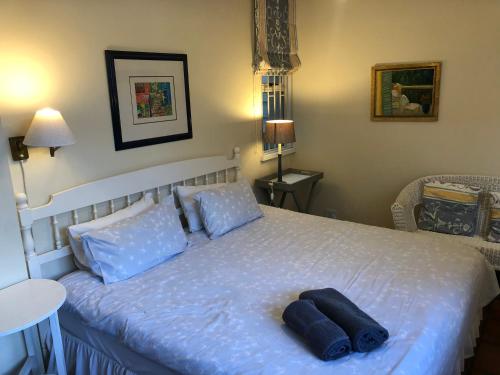 a bedroom with a white bed with blue pillows at Toms Cabin in Herolds Bay