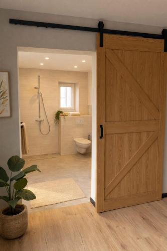 a bathroom with a wooden door with a shower and a toilet at Haus der alten Bäume - Retreathaus Hillesheim in Hillesheim
