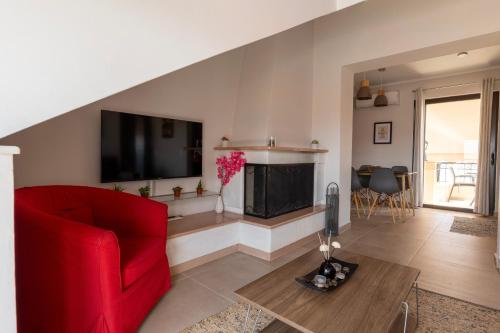 a living room with a red couch and a flat screen tv at Atticview Oropos in Néa Palátia