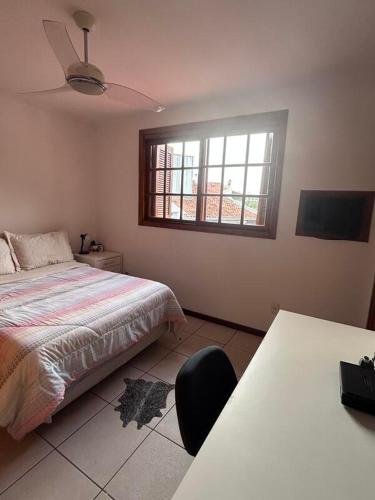 a bedroom with a bed and a table and a window at Alugo quarto com internet in Porto Alegre
