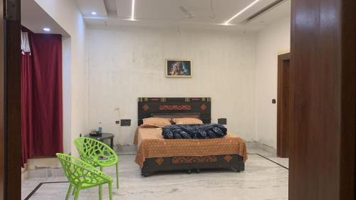 a bedroom with a bed and a green chair at Happy Homes in Jammu