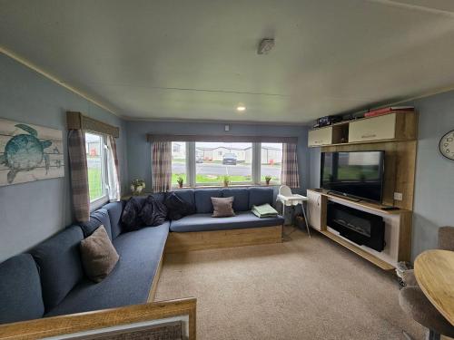 a living room with a blue couch and a tv at 3 Bedroom Deluxe Caravan at Haven Devon Cliffs in Exmouth