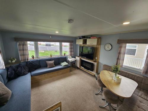 a living room with a blue couch and a table at 3 Bedroom Deluxe Caravan at Haven Devon Cliffs in Exmouth