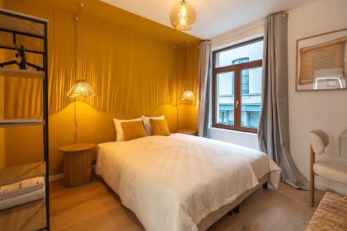 a bedroom with a bed with yellow walls and a window at Vandenbranden Suites in Brussels