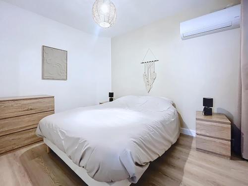 a white bedroom with a bed and a chandelier at Le Duc 1 - Appartement 2 pers - Centre Ville in Valence