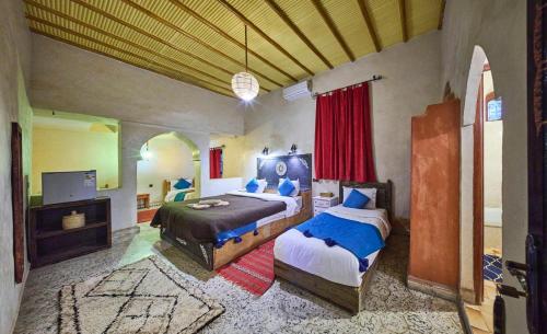 a bedroom with two beds and a flat screen tv at kasbah boutique mamouche in Adrouine