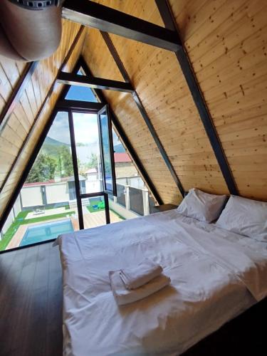 a white bed in a room with a large window at Emaar Afreem Pastar Qebele in Gabala