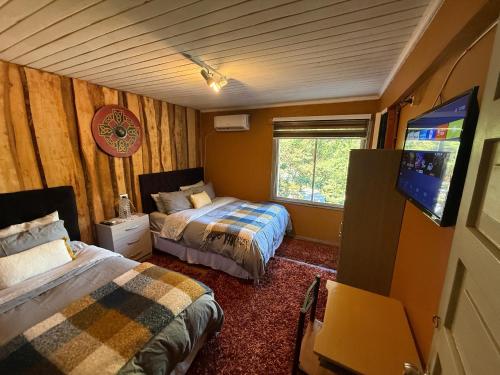 una camera da letto con due letti e una TV a schermo piatto di Hostal Suomi a Los Ángeles