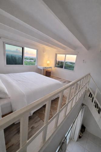 a white bedroom with a large bed and two windows at Aruba Villa on a Hill in Savaneta