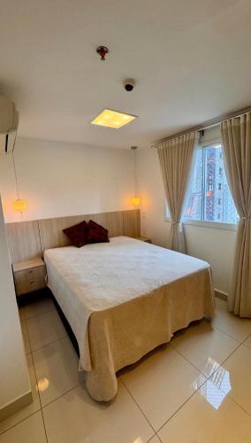 a bedroom with a large bed and a window at Metropolitan Mall in Goiânia