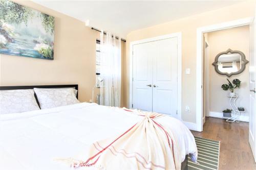 a bedroom with a white bed and a painting on the wall at Tonel Paradise 1BR private entrance Near JFK in Rosedale